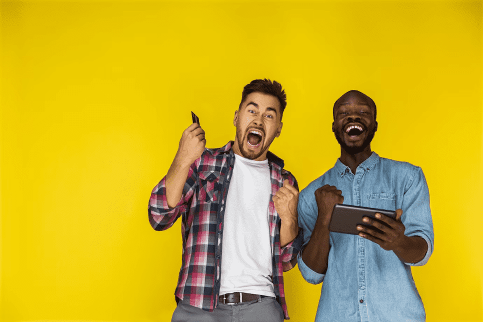 Duas pessoas comemorando com celular e tablet na mão